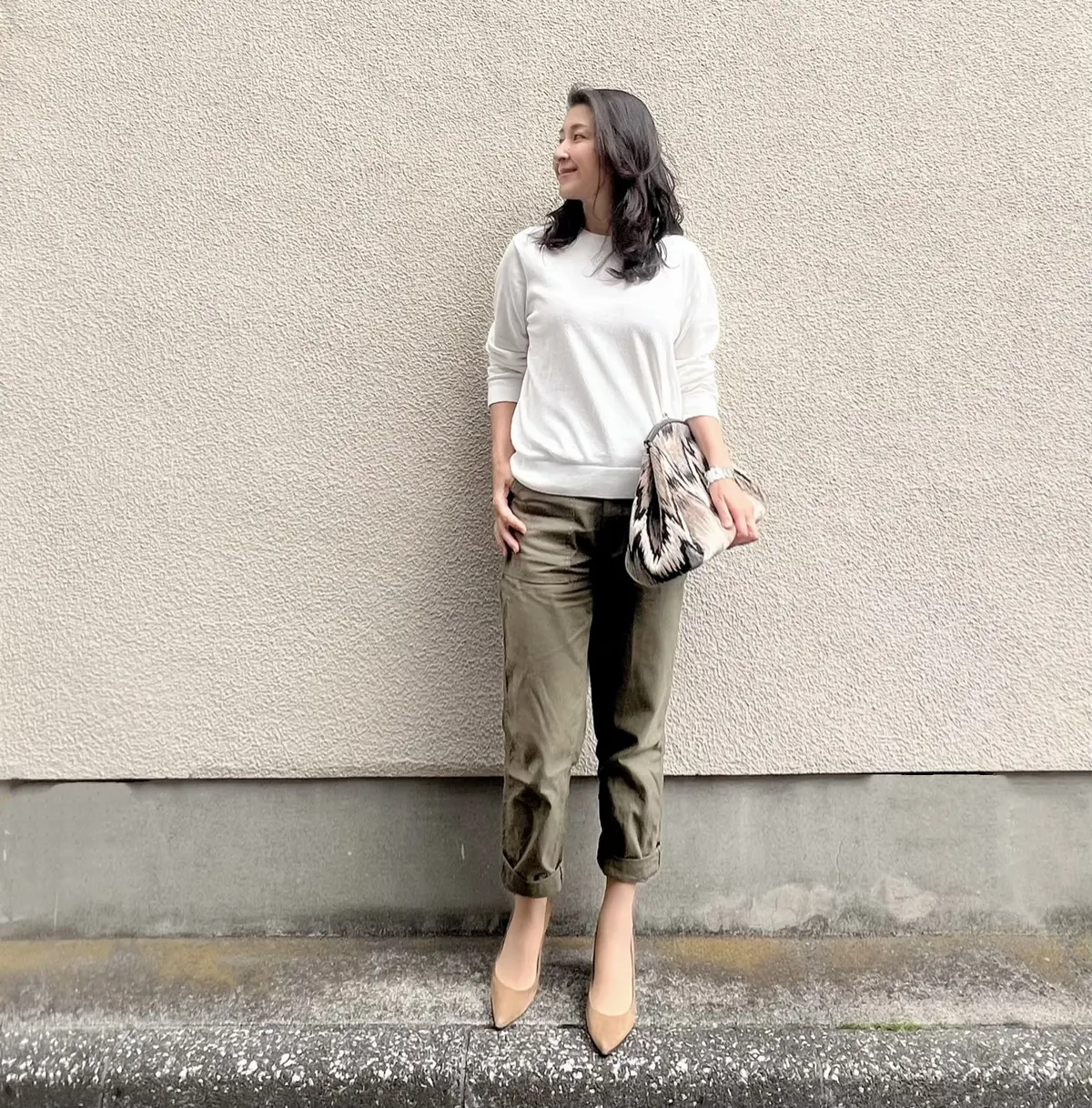 白ニット　カーキ色のベイカーパンツ　柄物の大きめクラッチバッグ　ベージュのパンプス