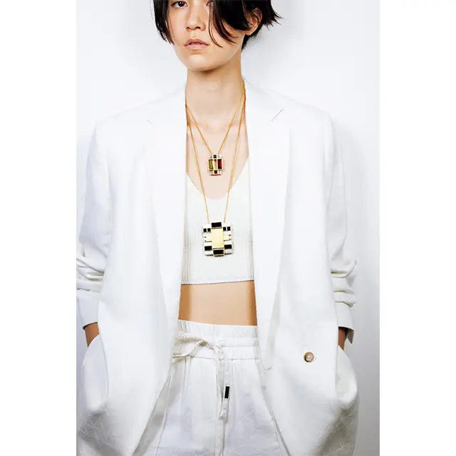 胸もとに重ねたペンダントは、アートな香り漂う大小のブローチ