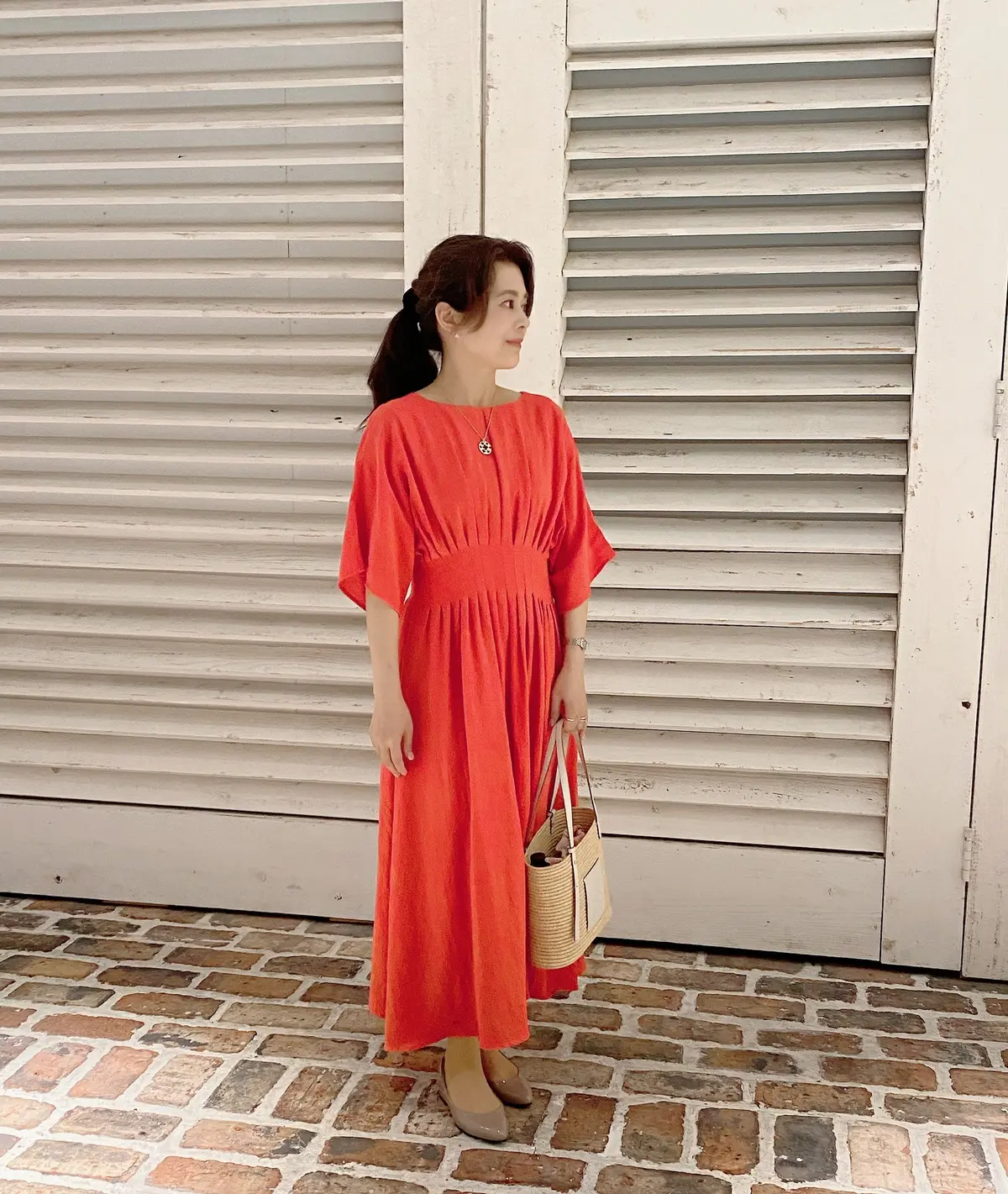 オレンジワンピースの横向き姿。夏らしい透け感と揺れ感が映える一枚。