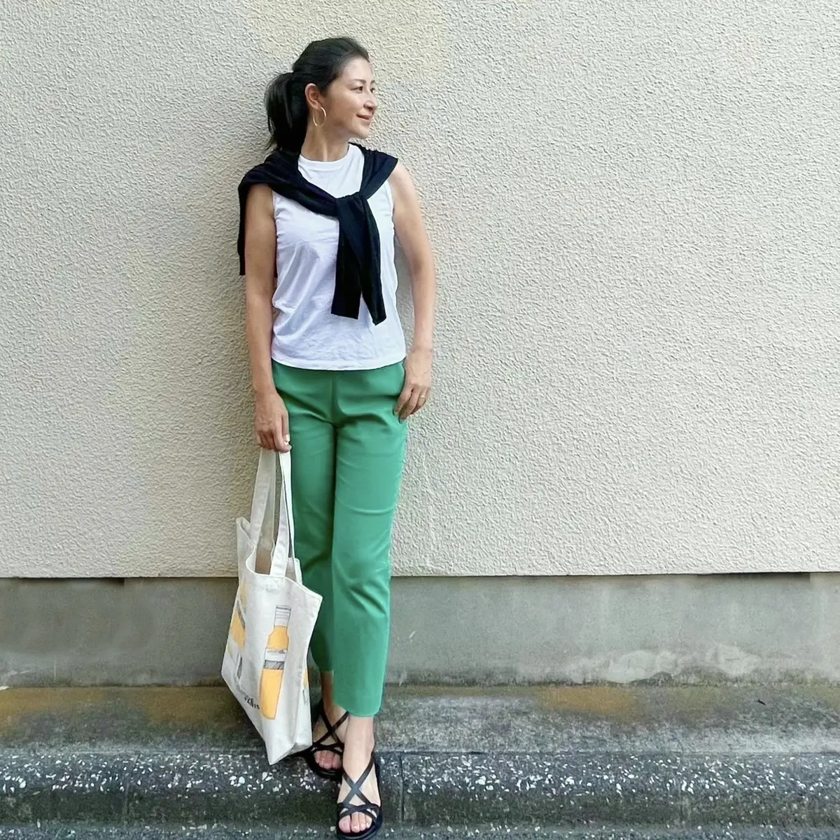 白Tシャツ、黒カーディガン、グリーンパンツ、黒サンダル、エコバッグ