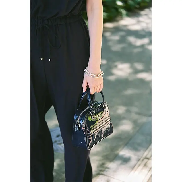 エナメルバッグのツヤや、ボリューム感のあるシルバーのアクセサリーを合わせて