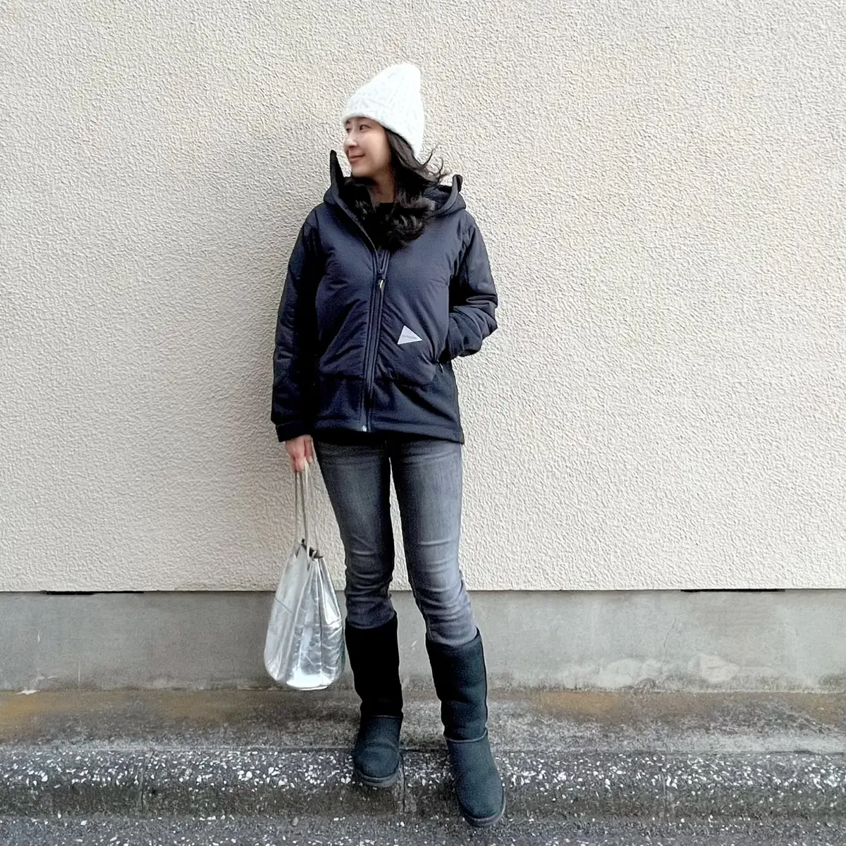 ユニクロの黒ウールニット、黒のスリムストレートデニムパンツ、黒ムートンブーツ、シルバーのバッグ、黒のフリースジャケット、白ニット帽