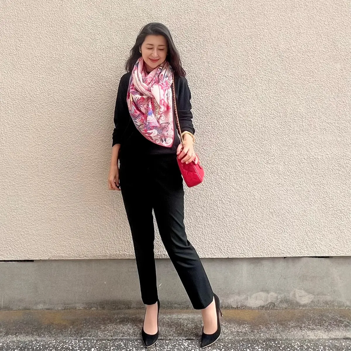 ユニクロ黒ニット、ユニクロ黒パンツ、黒パンプス、ピンク系柄物の大判ストール、赤バッグ