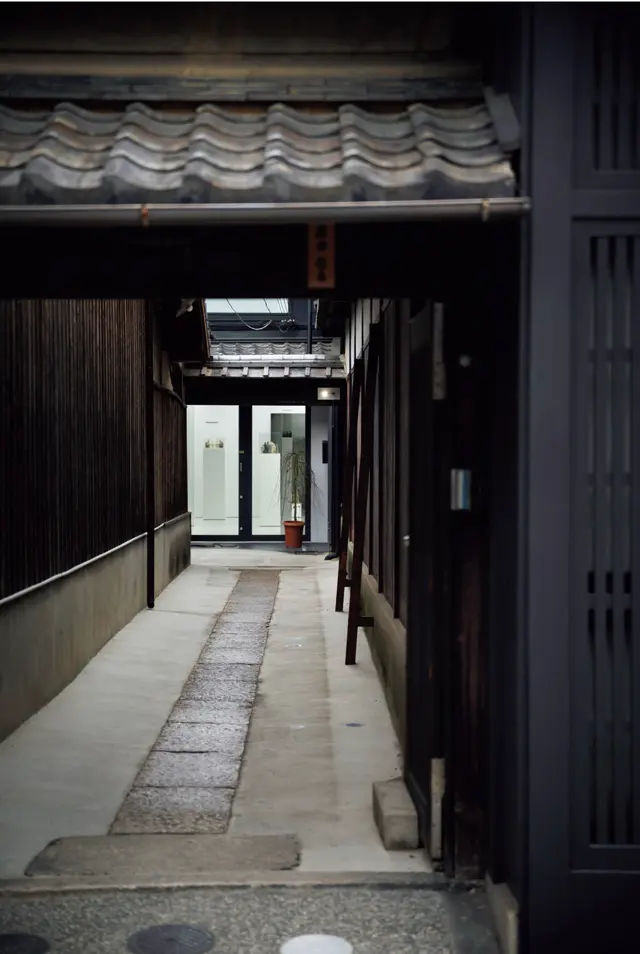 京情緒あふれる石畳の路地の先に見えるガラス張りのホワイトキューブ。