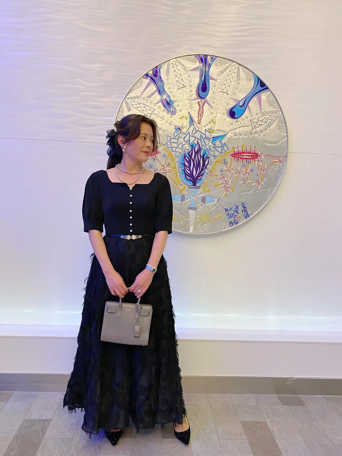 クルーズ船のフォーマルナイトに黒のロングドレスを着てアートの前でポーズを取るロングドレスの女性