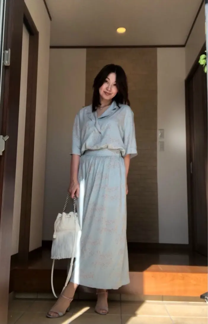 玄関　淡いブルーのセットアッップを着た女性