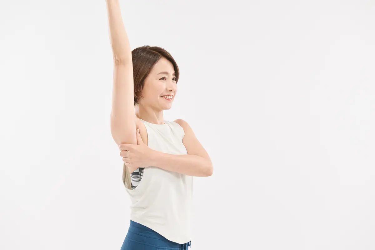 片方の腕をまっすぐ上に上げ、反対側の手の親指を脇に当て、残りの4本指は、脇の後ろ側に当てる