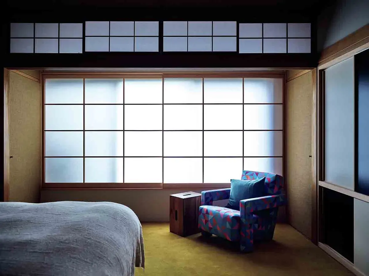 2階にある寝室。もとは和室と縁 側だった部屋をつなげ、からし色 のカーペット敷きに。窓辺には名 作ユトレヒト ソファとル・コルビ ュジェによるタブレ スツールを。 収納扉は白と黒に塗り分けた