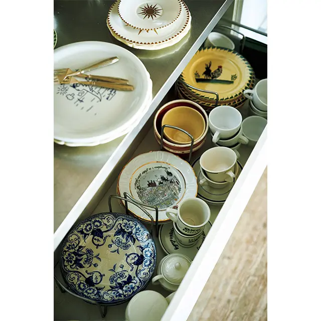 食器はひでこさんがパリの蚤の市で少しずつ集めた、楽しげな絵柄のフランスの古いものが多い。引き出しの中、手前のブルーの花柄はクレイユ・エ・モントロー