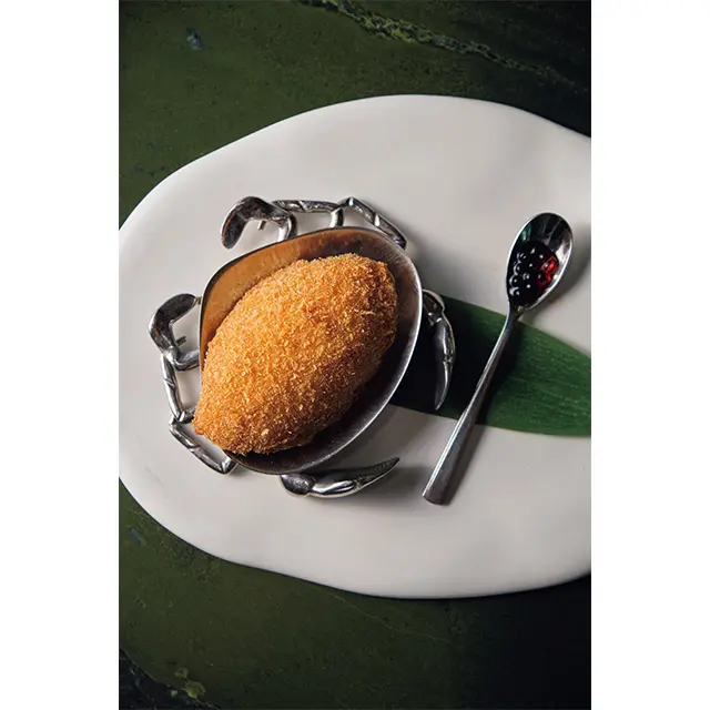 手作業でほぐしたカニ1杯分の身を玉ねぎと炒めてからオーブン焼きに。バルサミコ酢のビーズをつぶしながらいただく。「焗釀鮮蟹蓋（ジュニャンシェンシェガイ）」NTD730