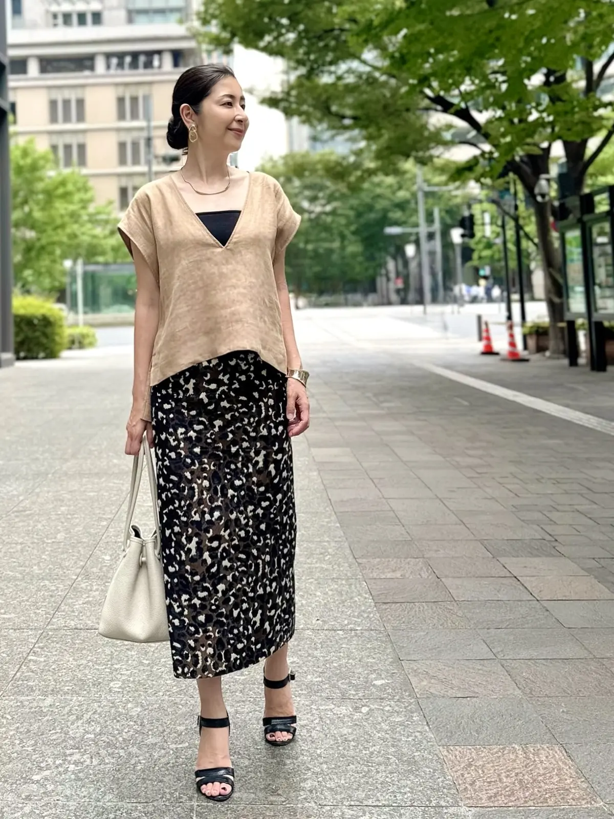 エクラプレミアムのキャメルの「リネンコンパクトジレ」、レオパード柄スカート、アイボリーのバッグ、黒サンダル