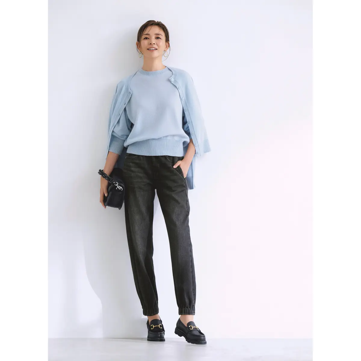 ペールブルーのニットトップスとカーディガンに黒デニム風パンツを合わせたコーディネート　モデル・SHIHO
