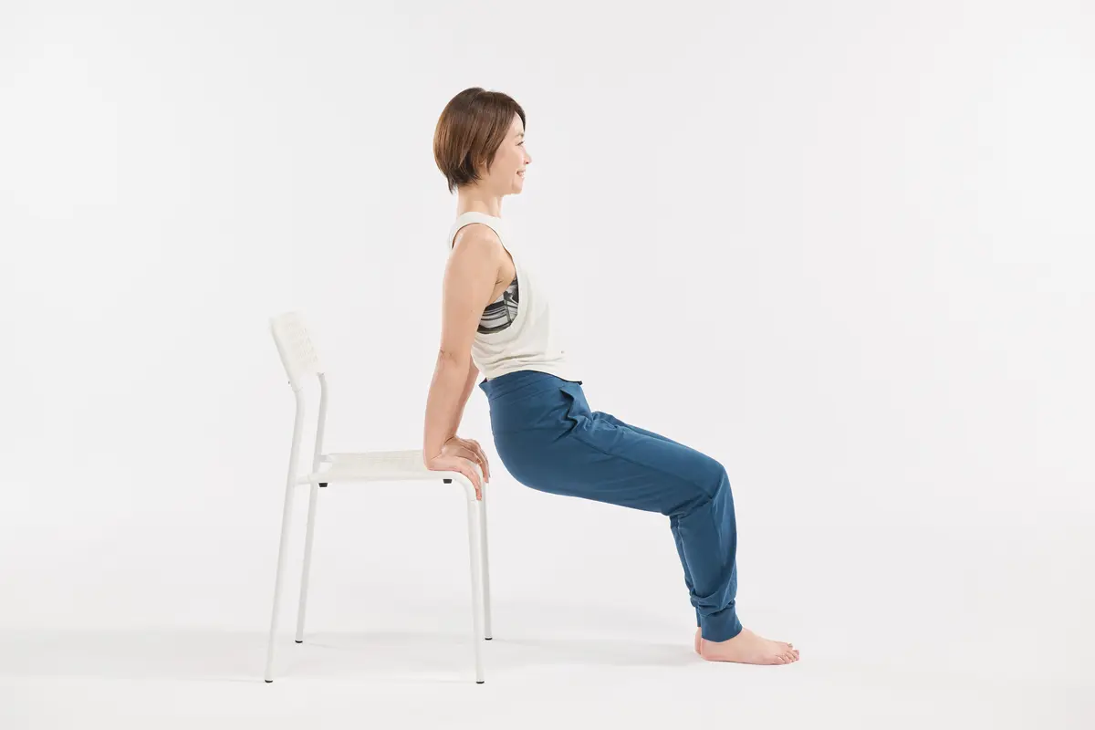 椅子の座面に両手を置き、指先を前に向ける。両膝は軽く曲げる