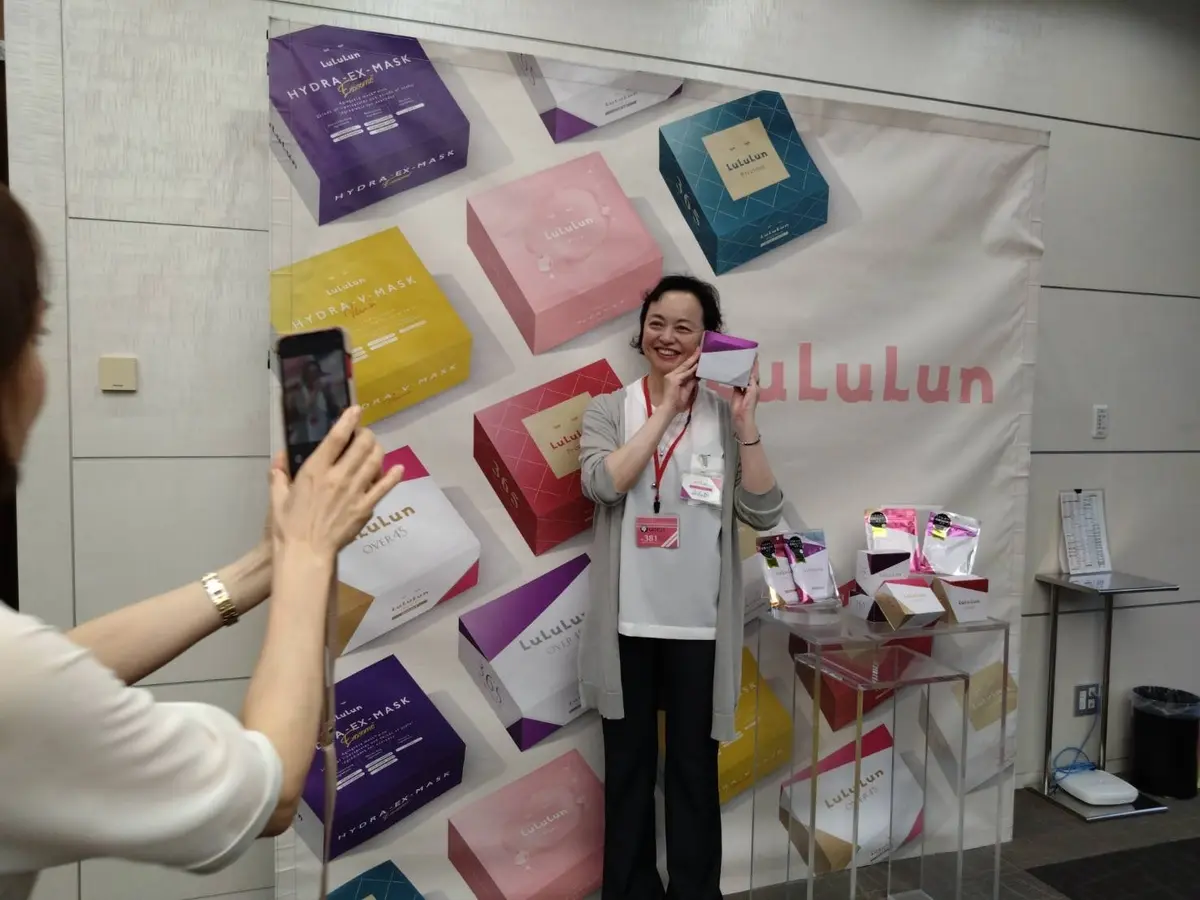 シートマスクを手に笑顔の女性と撮影する女性