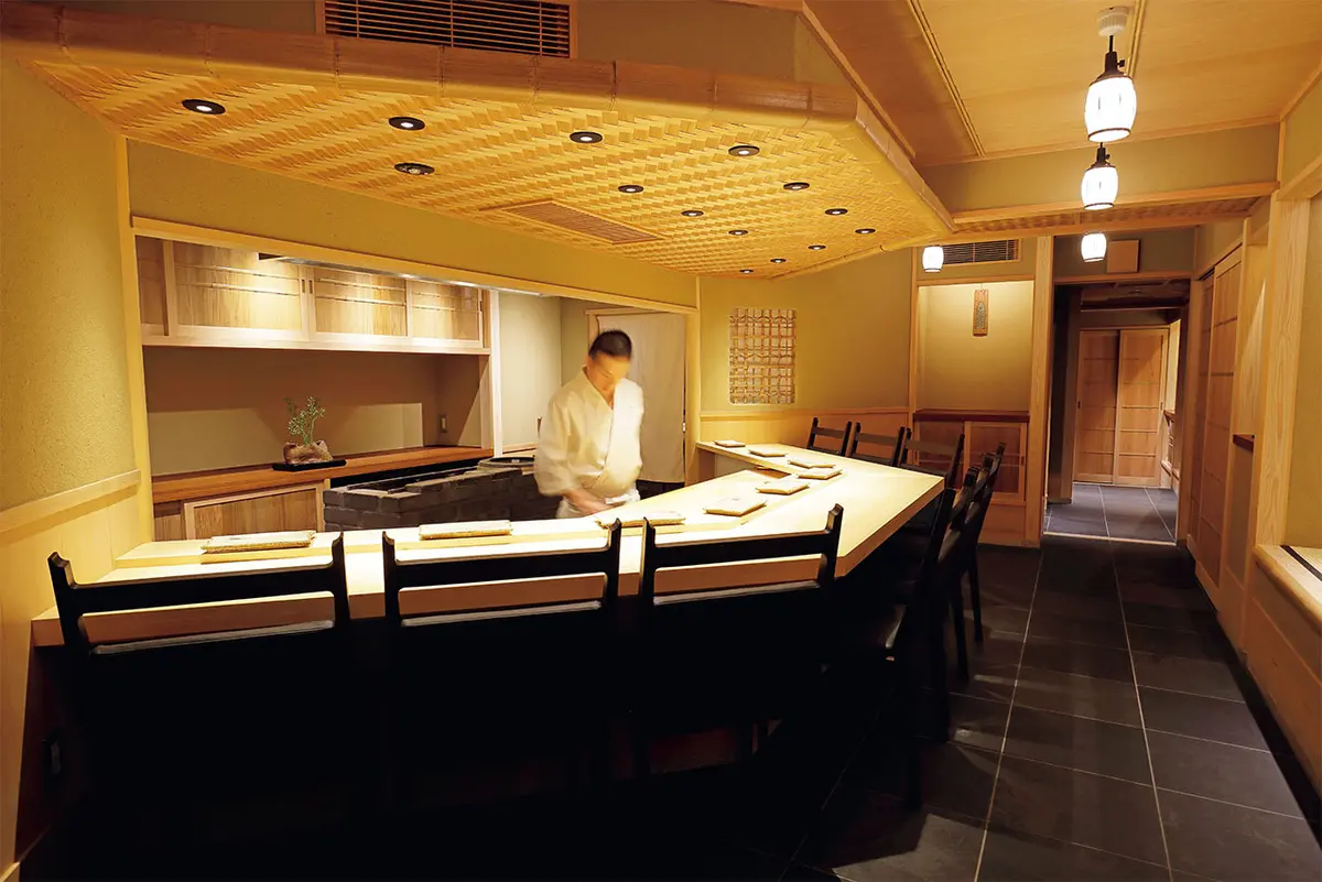 店主との距 離が近い白木の変形カウンター。竹と杉を用いた低めの網代 天井など、親密感が生まれる設計