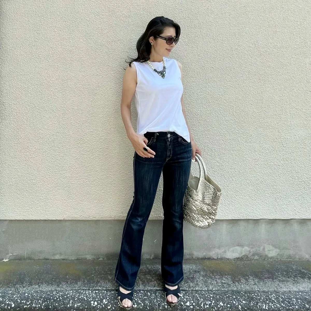 ユニクロの白ノースリーブTシャツ、ノンウォッシュのブーツカットデニム、シルバーの大きめバッグ、ネイビーのサンダル、パールとビジューのショートネックレス