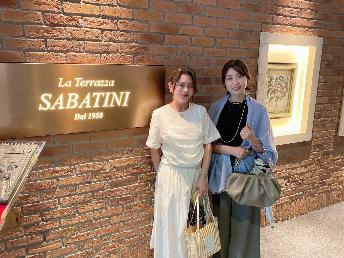 La Terrazza SABATINI表参道のエントランス前で撮影したJマダム2人のツーショット写真。骨格ストレート・ブルベ冬の筆者は白ワンピースとロエベのかごバッグ、hidemiさんは黒トップスにライトブルーのショールを羽織ったシックな装い
