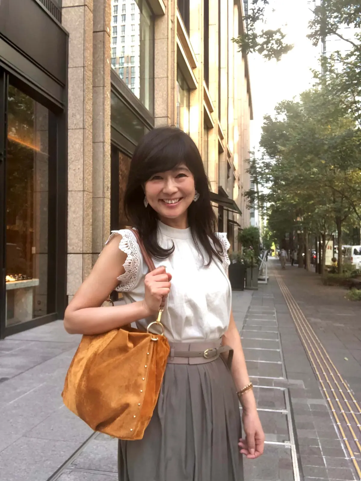 まだ暑いときの秋コーデ。ノースリーブの生成り色トップス、カーキ色のロングスカートに太ベルト。スエード調のキャメル色のバッグ。。