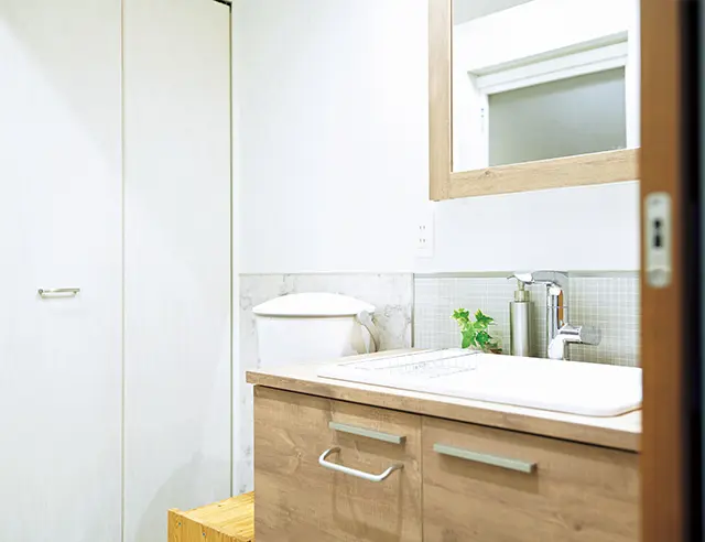洗面台もすっきりしたデザ  インにチェンジ。洗濯機は丸ごと、奥に新たに設けた収納へ