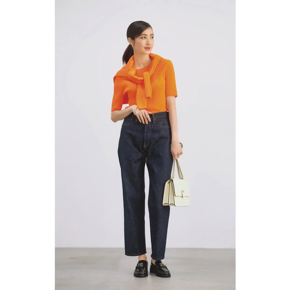 オレンジの半袖ニットと肩掛けしたカーディガンにインディゴのデニムパンツを合わせたコーデ　モデル・絵美里