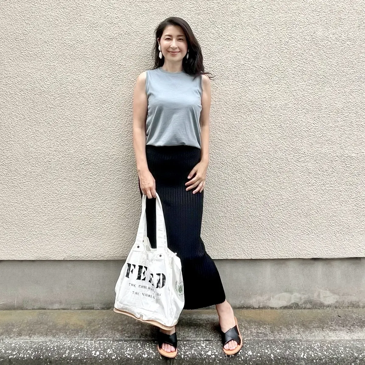 ライトブルーTシャツ、黒ロングタイトスカート、黒サンダル、白エコバッグ