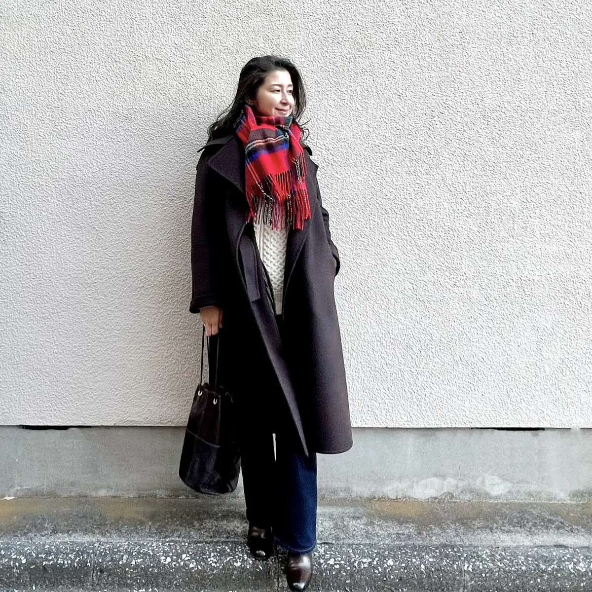 ユニクロの白アランニット、ネイビーのフレアーデニム、ブラウンのバッグ、ブラウンのショートブーツ、赤系チェック柄のストール、ブラウンのロングコート
