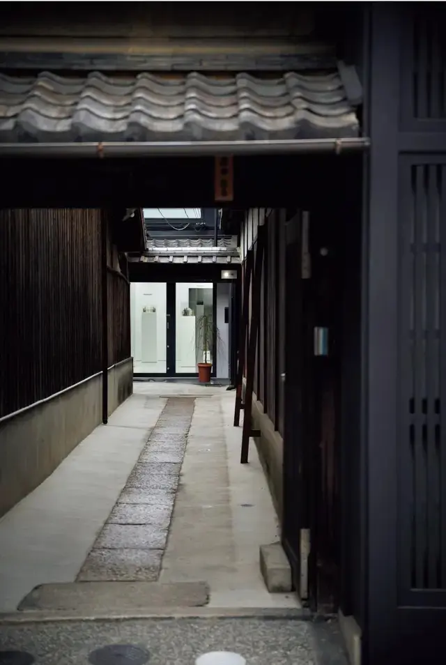 京情緒あふれる石畳の路地の先に見えるガラス張りのホワイトキューブ。伝統と革新が融合する京都らしい光景