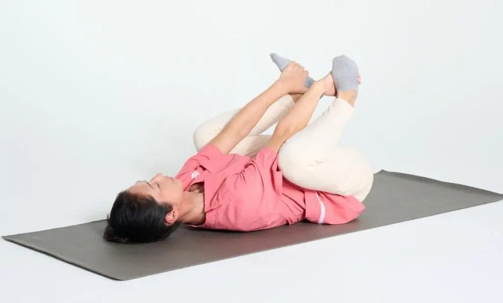 OurAge×Webエクラ　①あお向けに寝て、左右の膝を曲げ、両手を膝の内側から伸ばして、足裏を内側からつかみます。