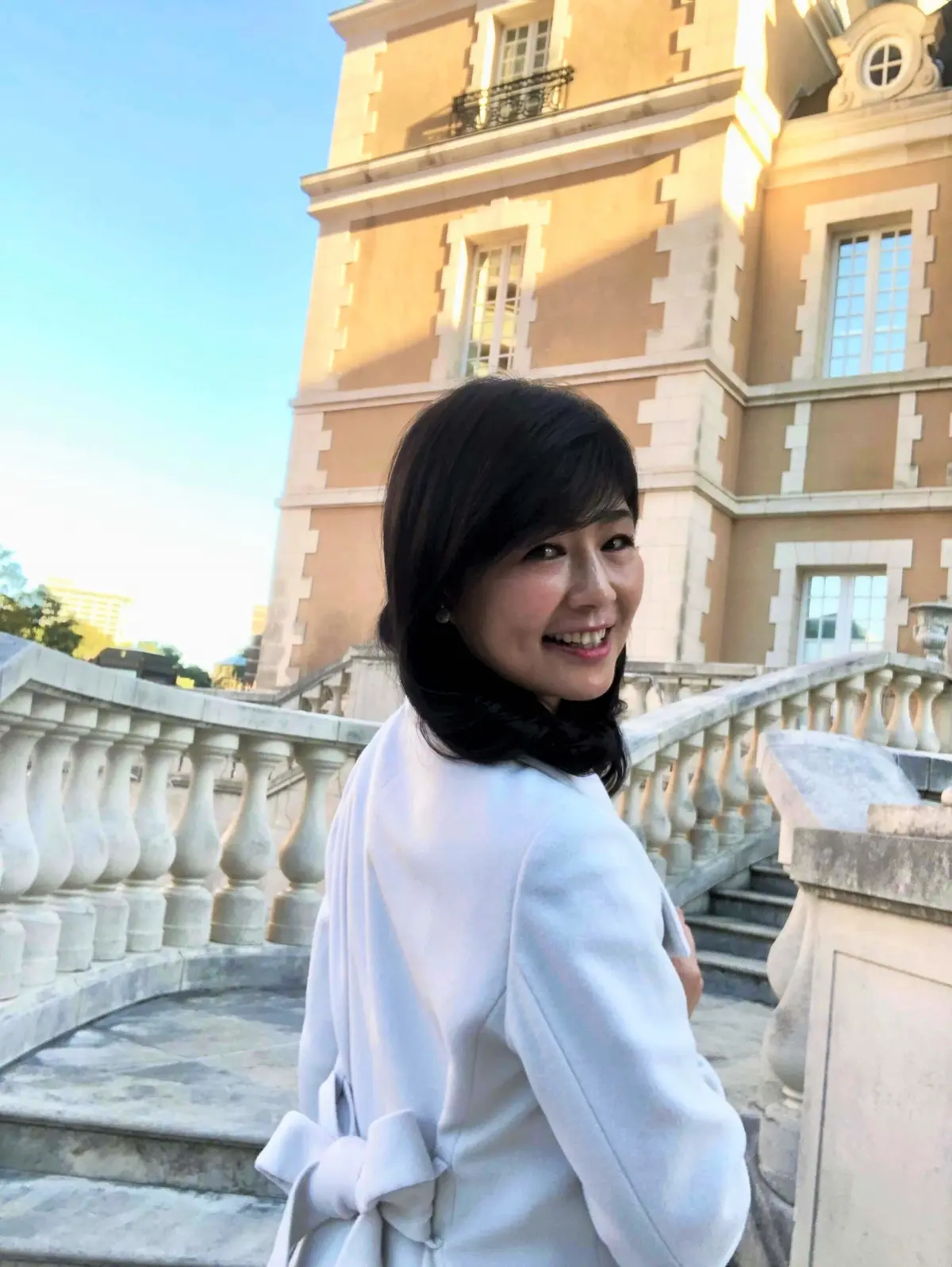 「ロペ」の白ロングコート。後ろ姿。付属のベルトを後ろでリボンしてウエストを絞ったスタイルに。