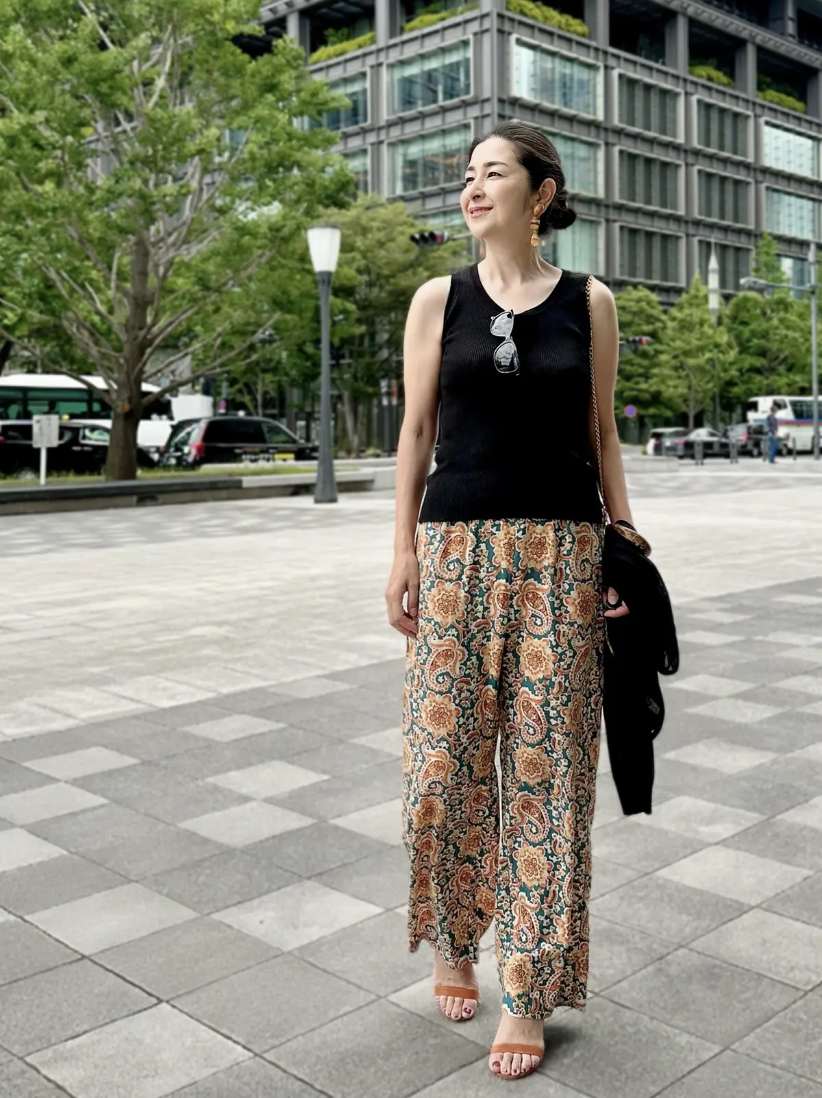 オレンジ系柄パンツ、黒ノースリーブニット、黒カーディガン、キャメルサンダル