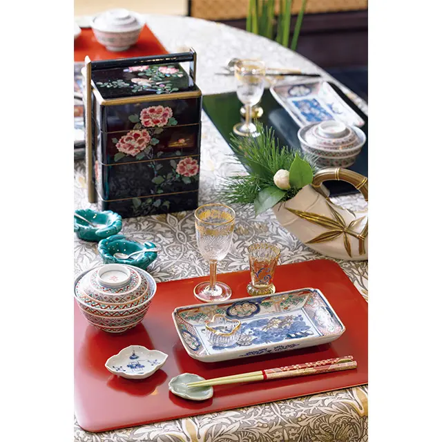 「古伊万里は色絵を 選ぶとお正月らしく華やかさが増しま す。アンティークの塩入れは凝ったデ ザインが多く、豆皿と組み合わせ、黒 豆や珍味をちょこちょこ盛りつけるの も楽しいですね」。古伊万里・色絵長皿 （参考商品）、皿にのせたドームの塩入れ ￥66,000、古伊万里蓋付茶碗￥38,500