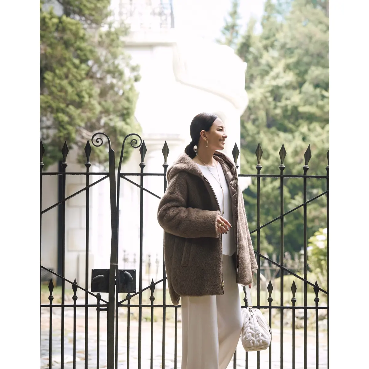 ブラウンのファーフードコートに白トップスとオフ白パンツを合わせたコーディネート　モデル・RINA