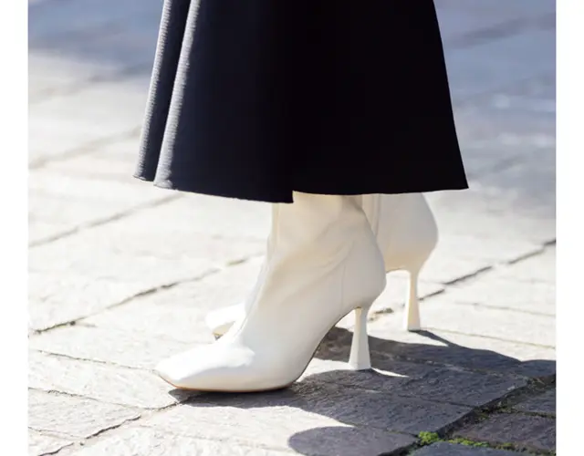 揺れる黒のロングスカート。黒ブーツを合わせがちなところを、白のショートブーツというモダンなチョイスが新鮮