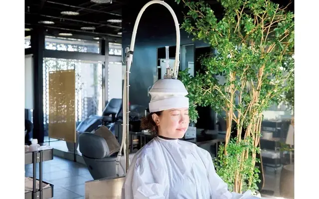 真空含浸装置（写真）を頭にセットし、蓄積されている老化脂を取り除く。頭皮を真空状態にして吸引し、毛穴深部に詰まった汚れを引き出す。途中、ヘッド装置に育毛剤を注入し、加圧噴射しながら剤を地肌や毛穴に浸透させる。