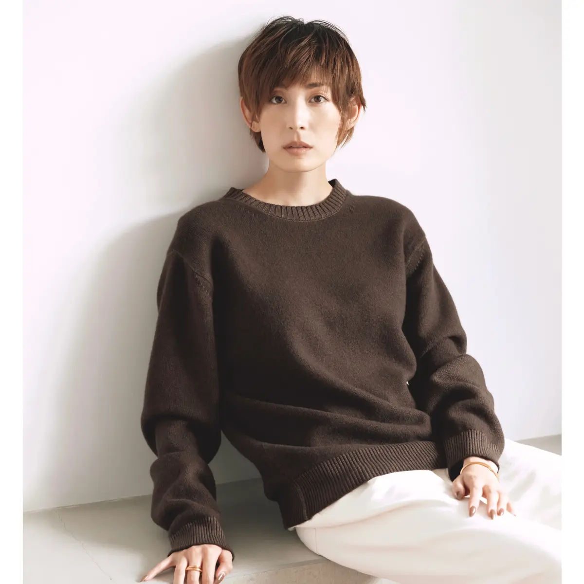 ブラウンのクルーネックニットとホワイトパンツのコーデ　モデル・LIZA
