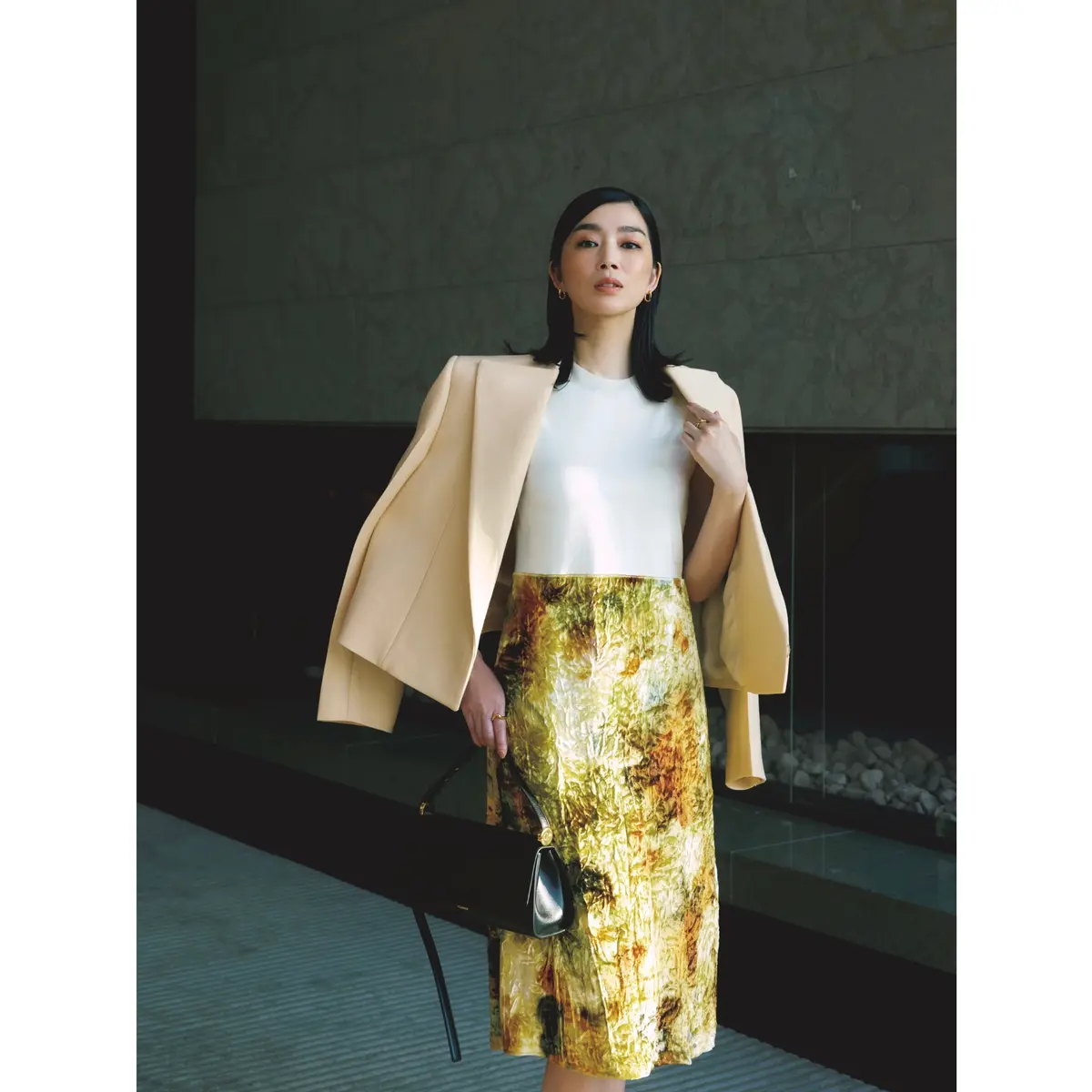 ベージュジャケットに白トップスとイエロープリントスカートがドッキングしたワンピースを合わせたコーディネート　モデル・ゆうき