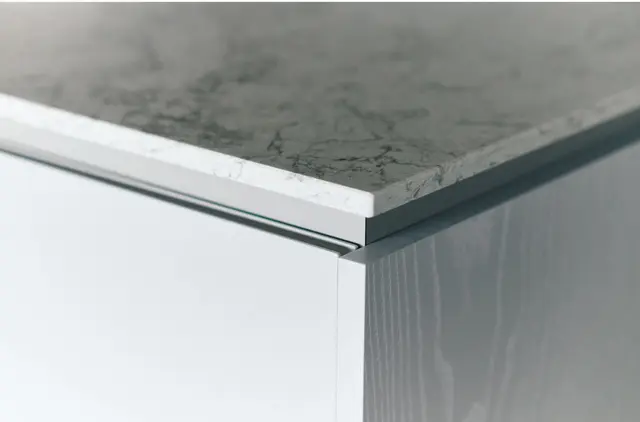 カウンタートップは真鍮色の水栓金具に合うシーザーストーンのグレー系を選択。断面も美しい