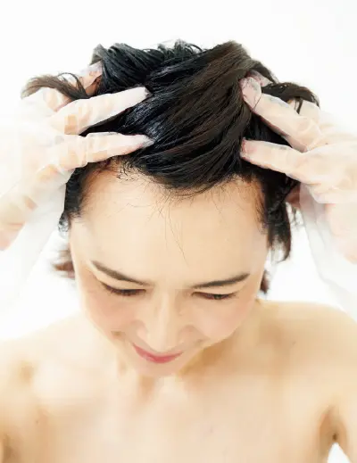 髪にのせたトリートメントを指で根元に行き渡らせる