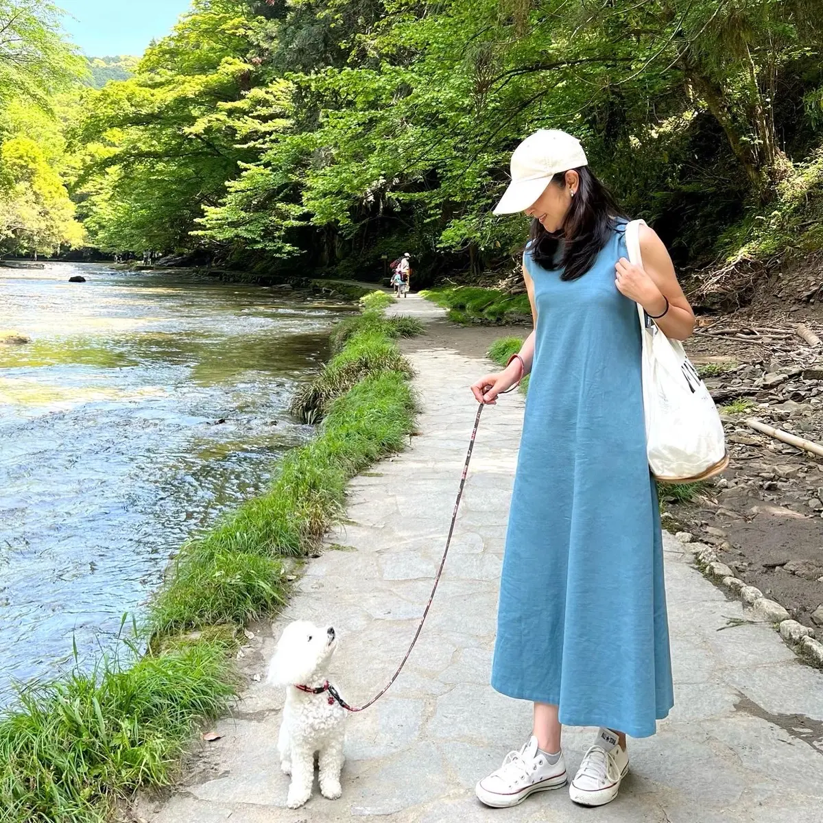 ブルー系ワンピース、白のスニーカー、白のトートバッグ、ライトベージュのキャップ