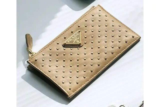 ベージュ×ゴールドのスタッズに大人のひそかなパンクマインドを宿して。背面にカードケースのスリットがあり、スマートに出し入れできる。