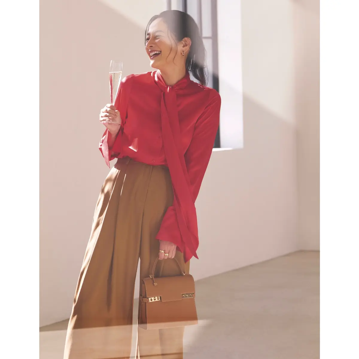 赤のボウタイブラウスにキャメルのタックパンツを合わせたコーディネート　モデル・熊沢千絵