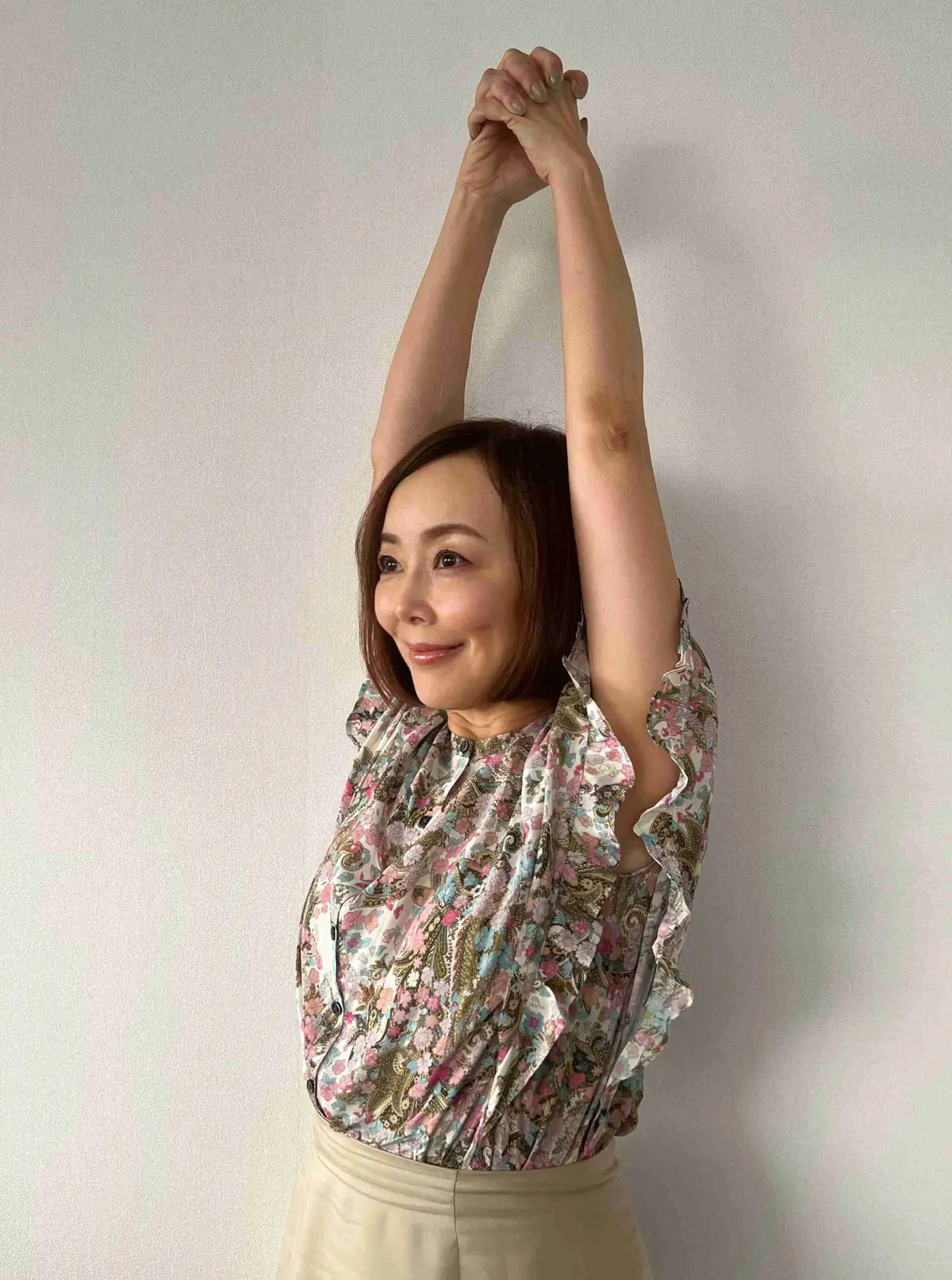 腕をのばし、頭の上で手を組む。肩に痛みが出る場合は、辛くない位置で手を組み、上半身の筋肉をストレッチ。