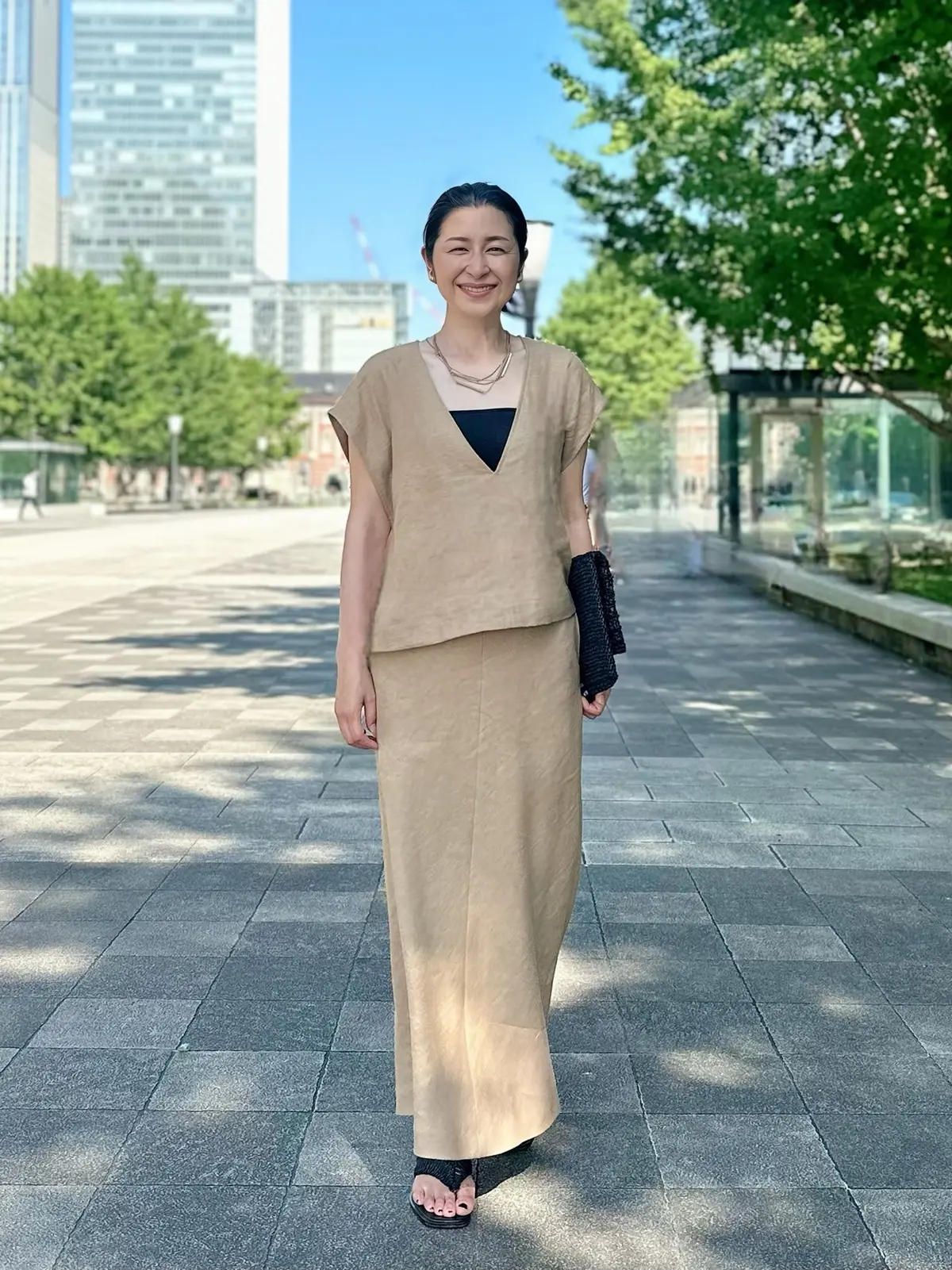 エクラプレミアム「リネンコンパクトジレ＆フレアスカート」　キャメル　黒のクラッチバッグ、黒のサンダル