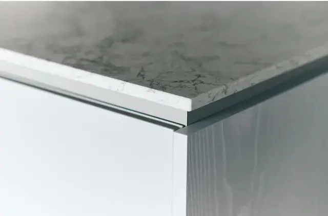 カウンタートップは真鍮色の水栓金具に合うシーザーストーンのグレー系を選択。断面も美しい