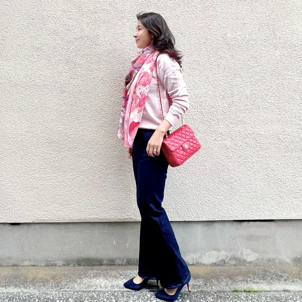 ピンクニット、柄物大判ストール、赤のキルティングバッグ、フレアデニム、ネイビーのパンプス