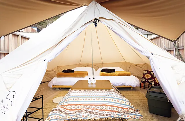 セミダブルベッ ドを2台設置したテント。冬場はこたつが置か れる。ほかにキャビン型宿泊施設も