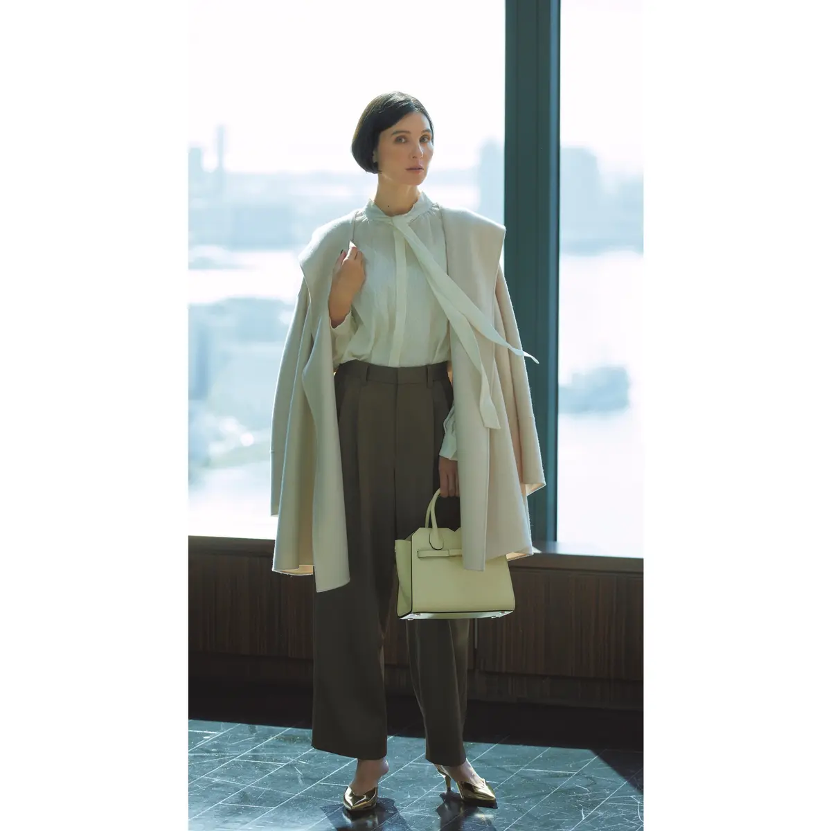 白ボウタイブラウスとタックパンツにしろアウターをはおったコーデ　モデル・田沢美亜