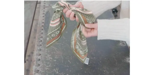 「余った2つの角を結び目の中に折り込み棒状にする。そのまま首に巻いて後ろで結んで完成」