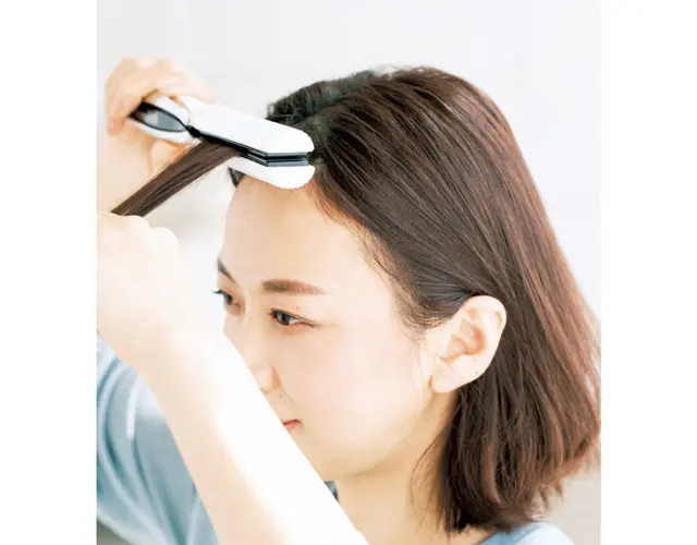 前髪の根元をアイロンではさむ