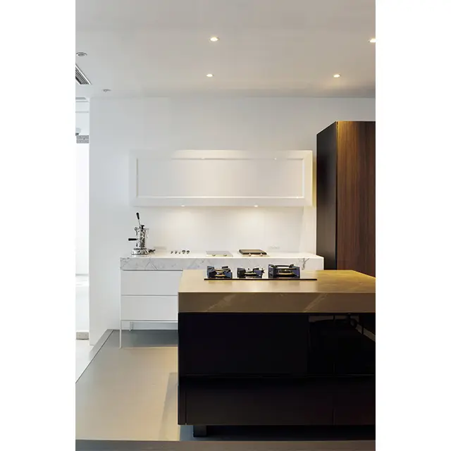 ）奥は創業当時から手がけてきた鏡面仕上 げのキッチン。吊り戸棚の一枚扉が目をひく。 カウンタートップはイタリア産の天然大理石。 アイランドと横の収納扉は黒で引き締めてい る。